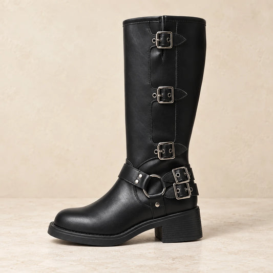 Black multi-buckle harness boot on warm cream studio background
