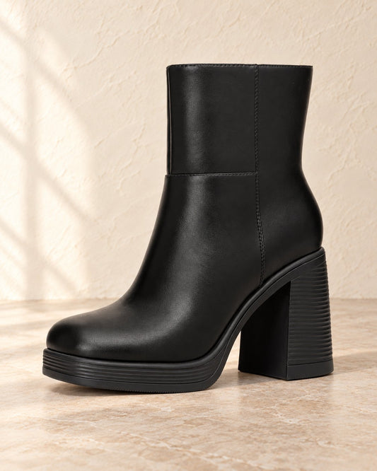 Black platform ankle boot on warm cream plaster and pale stone studio background